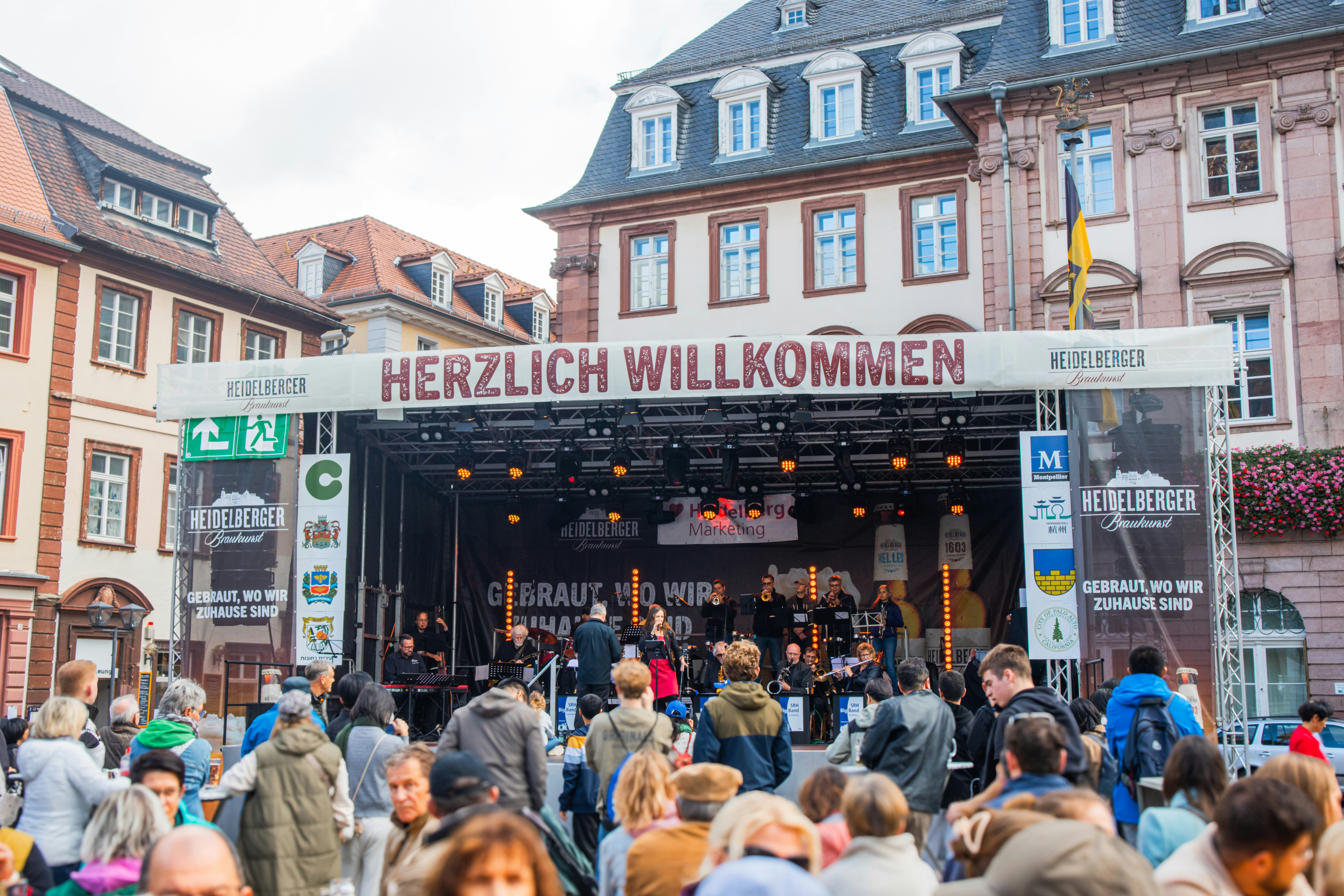 People gathered at an outdoor concert stage with banner
